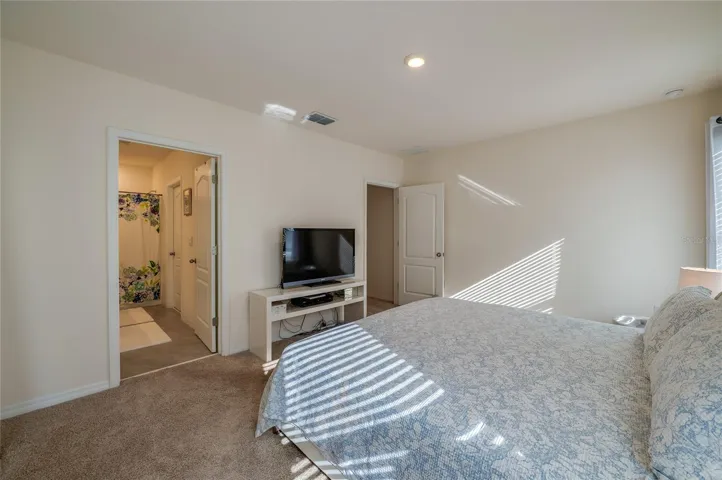 Additional view of the bedroom highlights its generous proportions and convenient direct access to the adjoining bathroom.