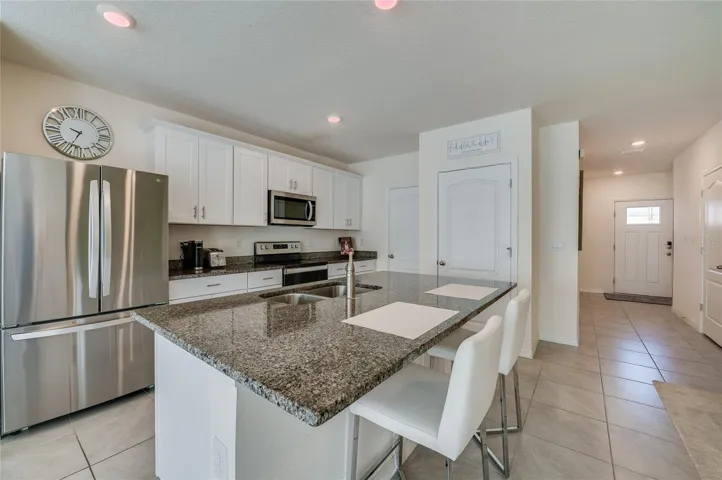 Spacious center island provides abundant prep and serving space, complemented by granite countertops, stainless steel appliances, and ample cabinetry.