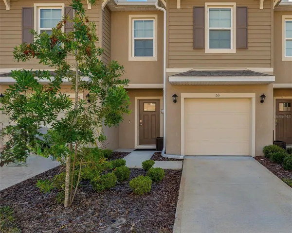 Attractive townhome exterior with an attached garage, covered entry, and neatly maintained landscaping.