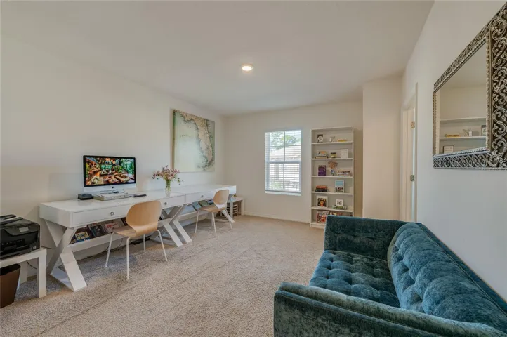 Spacious primary bedroom offers generous room for a complete bedroom setup, with neutral carpeting, recessed lighting, and natural light from the window.