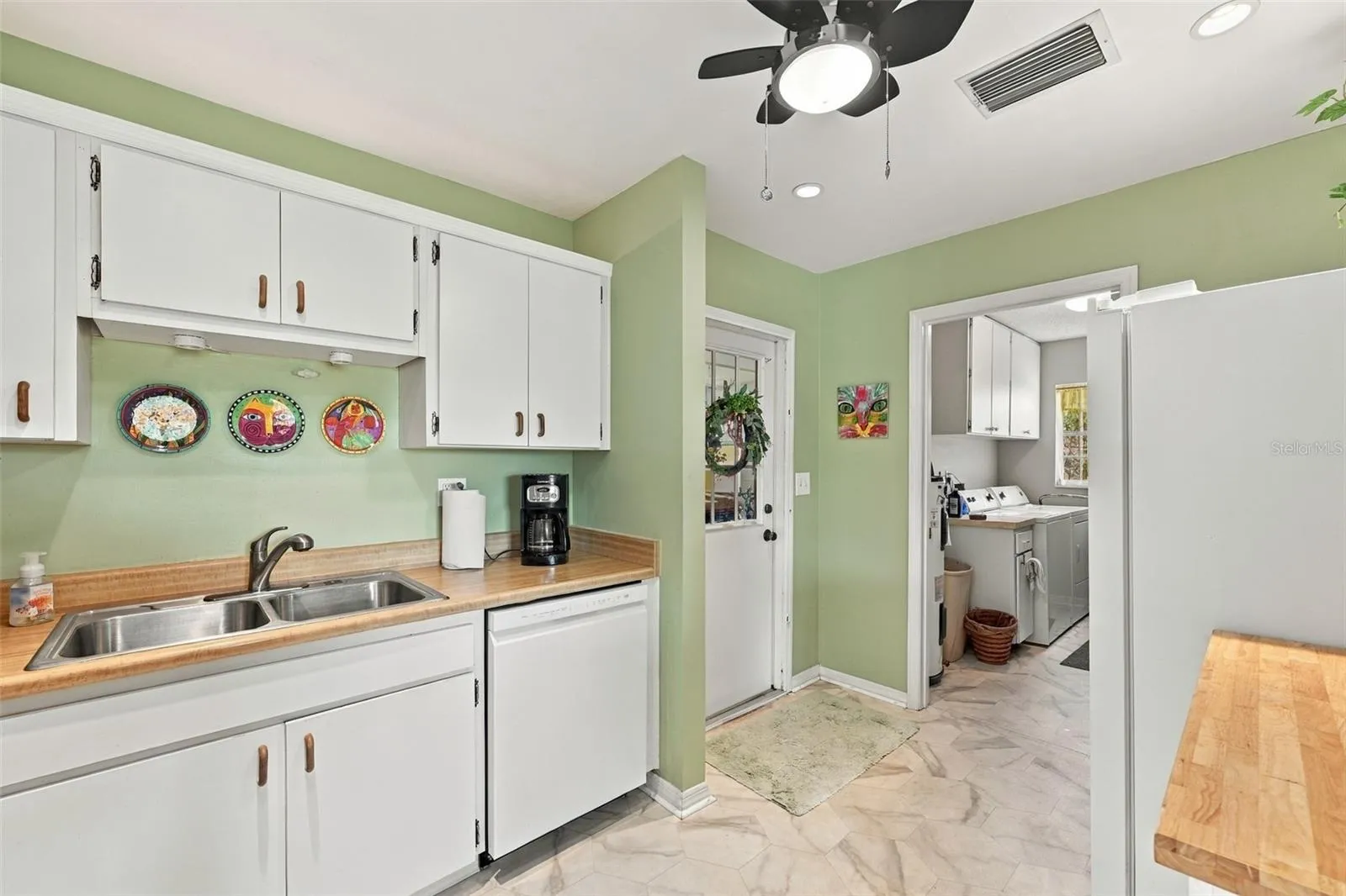 Simple all white cabinetry gives this room a sparkling clean appearance with bright recessed lights and a ceiling fan.