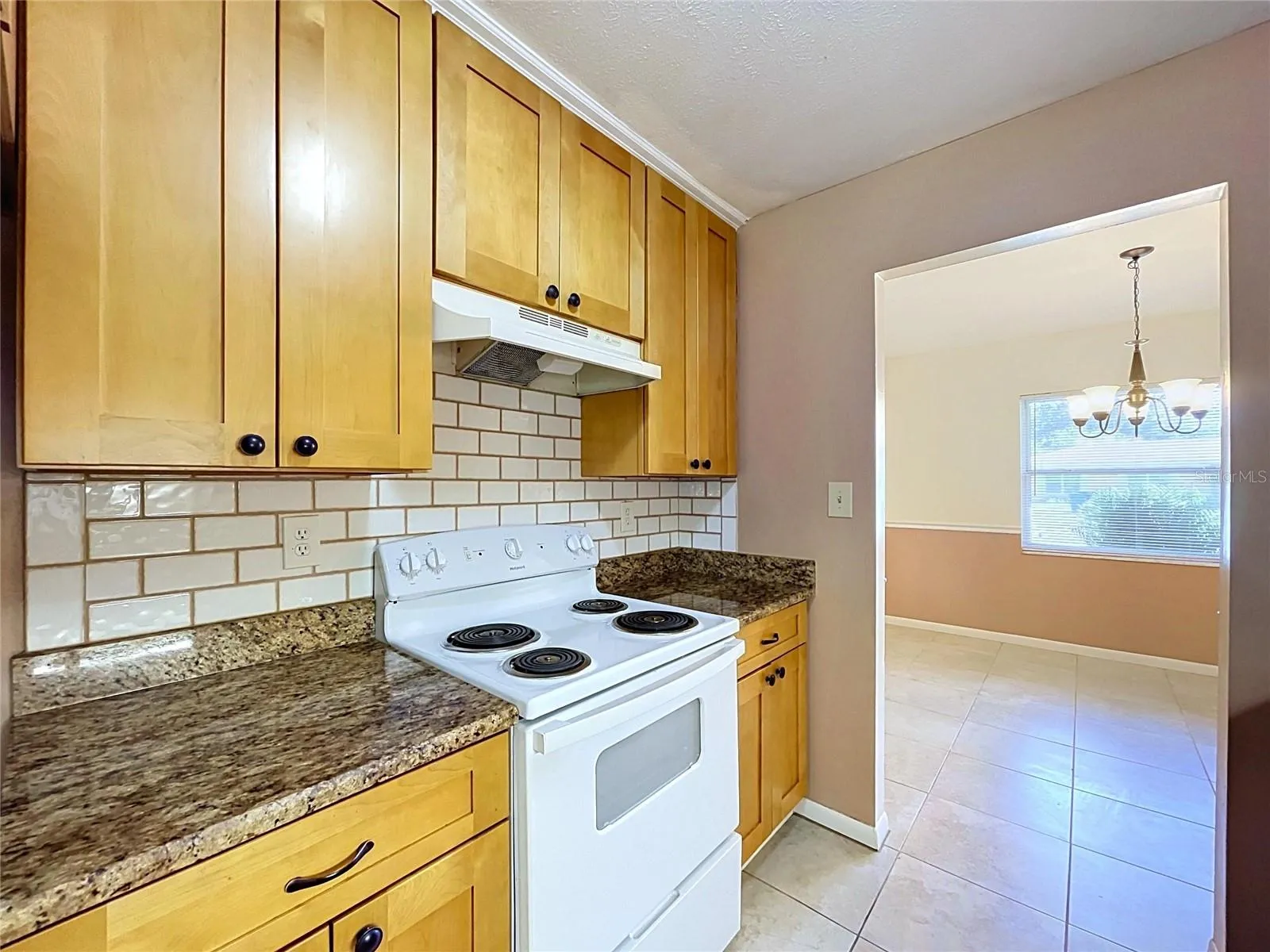 Kitchen stove, wood cabinets, granite countertops, tile backsplash