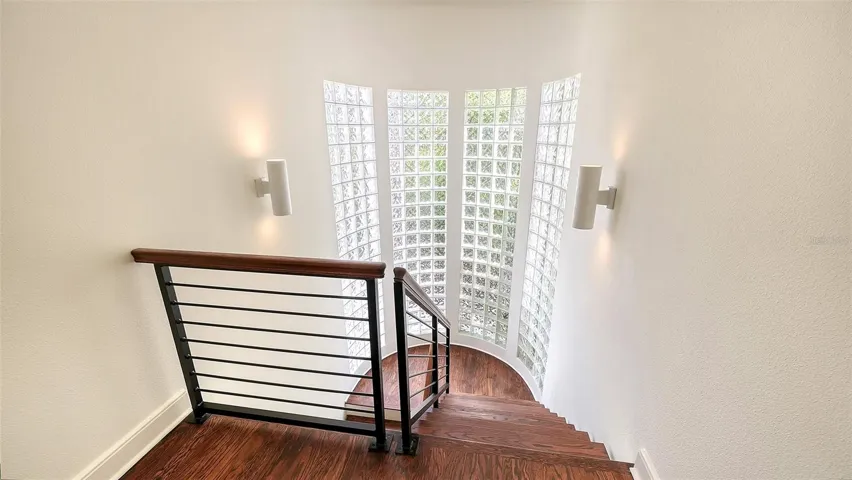 Glass windows line the stairway to the primary suite