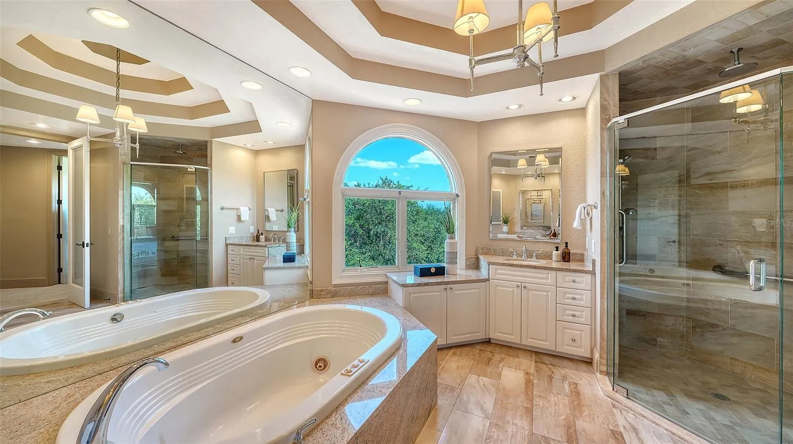 A spacious glass enclosed shower and soaking tub complement the beautifully appointed primary suite.