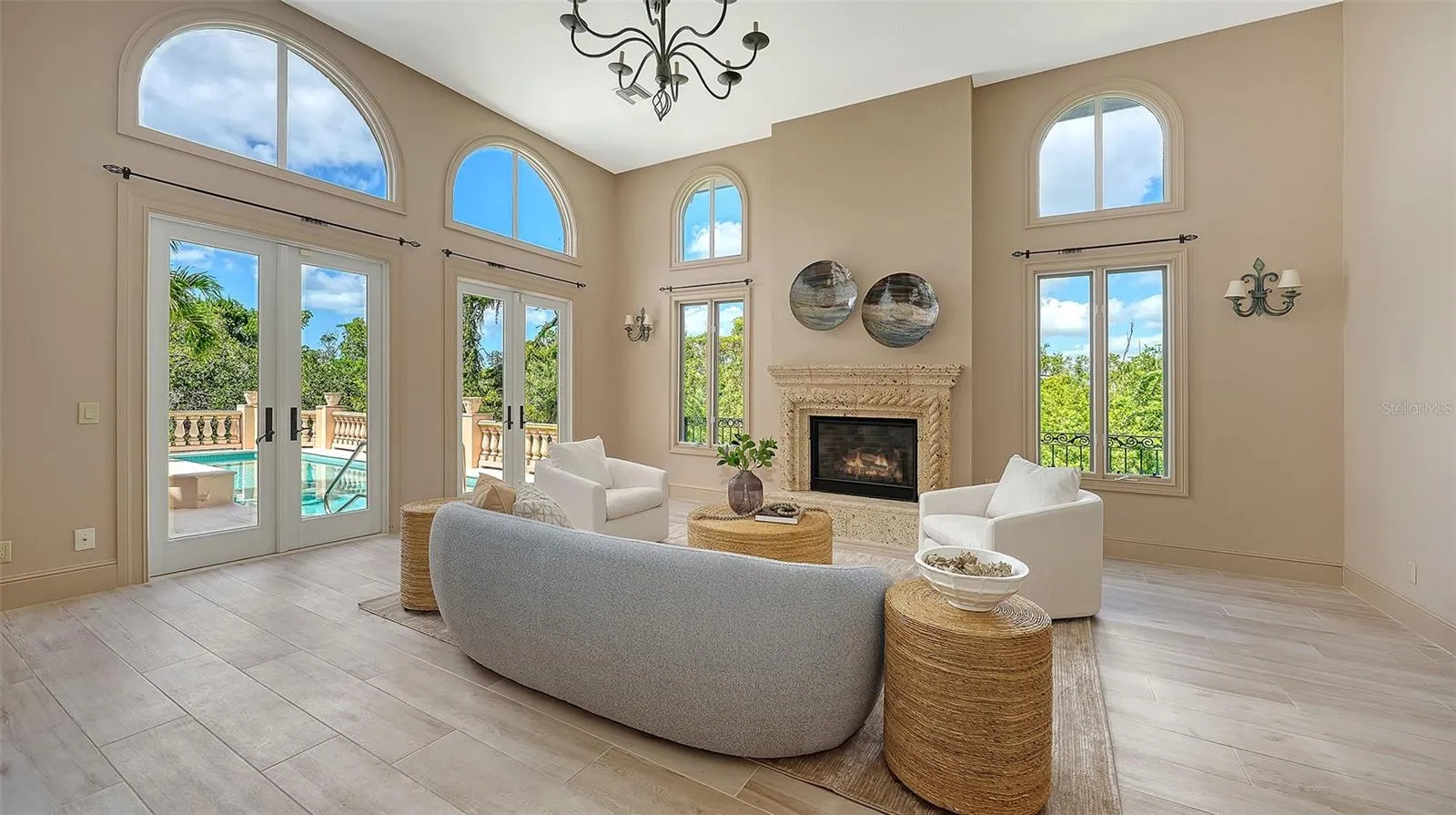 Walls of windows and French doors fill the great room with natural light while connecting the interior to the surrounding landscape.