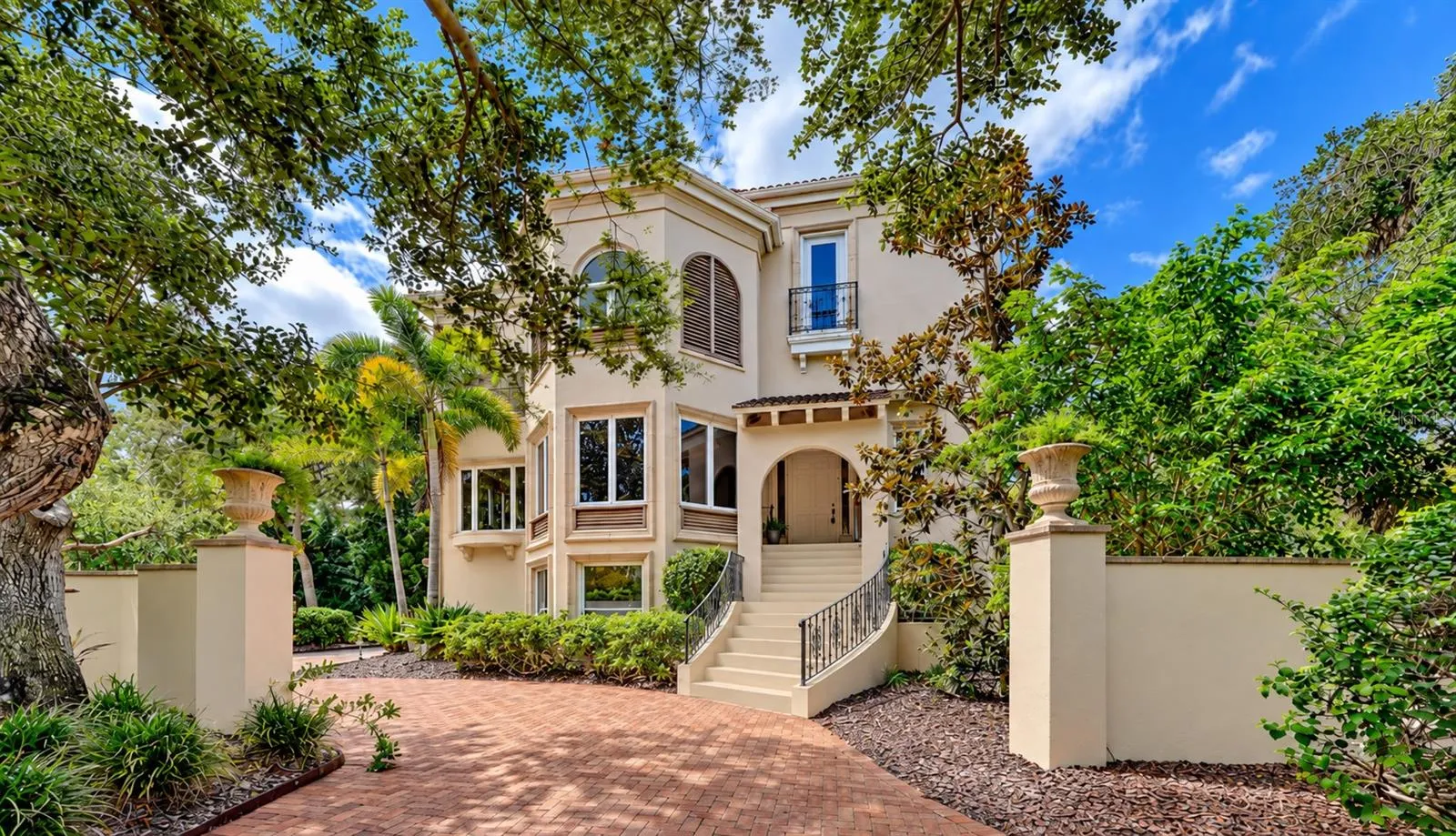 Mizner inspired architecture and lush tropical landscaping create an impressive introduction to this private bayfront residence.