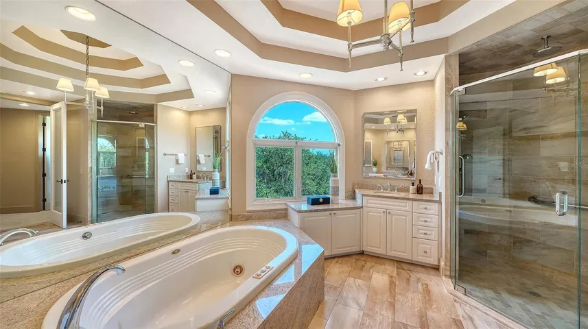 A spacious glass enclosed shower and soaking tub complement the beautifully appointed primary suite.