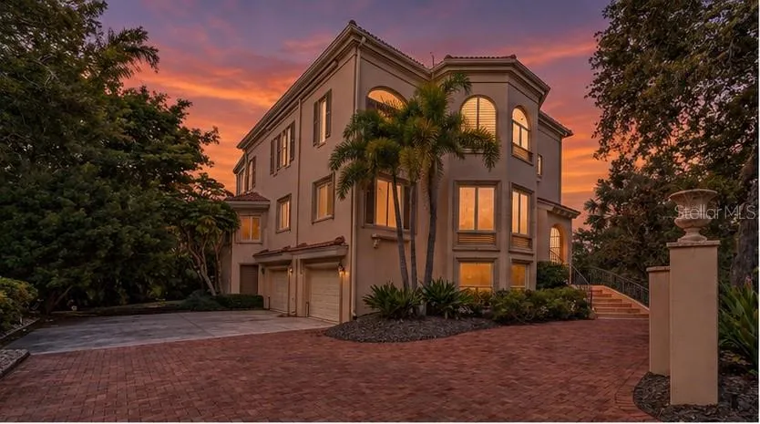 The home's distinctive architecture takes on a dramatic presence beneath Sarasota's colorful evening skies.