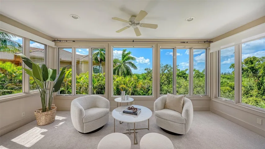 A light filled sitting area within the primary suite provides a serene place to relax while enjoying views of the tropical surroundings.