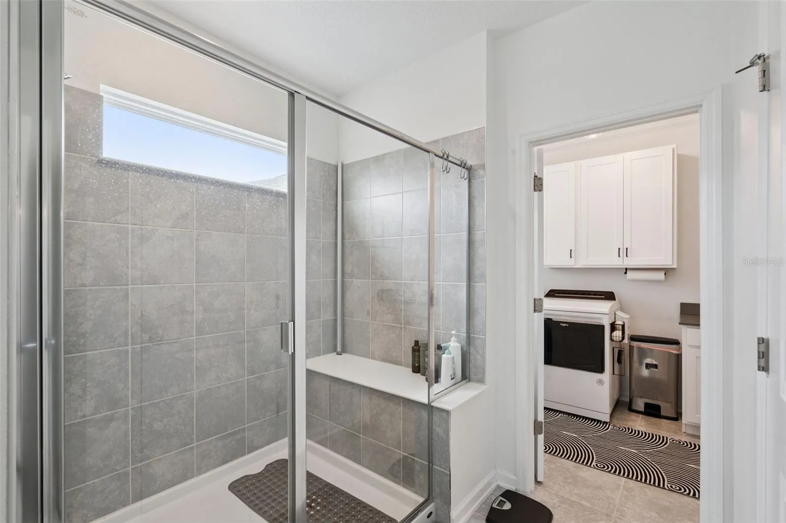 Owner's suite bathroom shower with built in seating, easy access into the laundry room