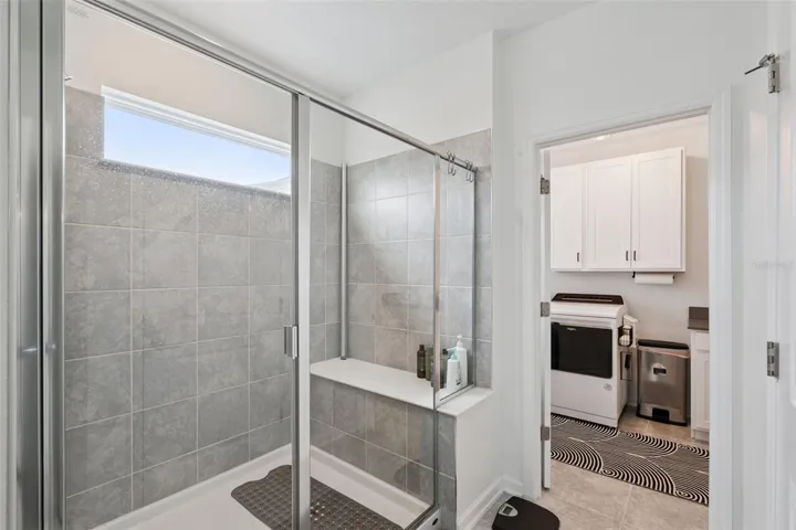 Owner's suite bathroom shower with built in seating, easy access into the laundry room