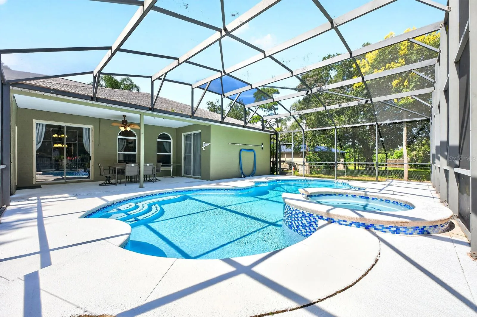 The NEWLY RESURFACED INGROUND POOL AND SPA are nestled beneath an oversized screened lanai.