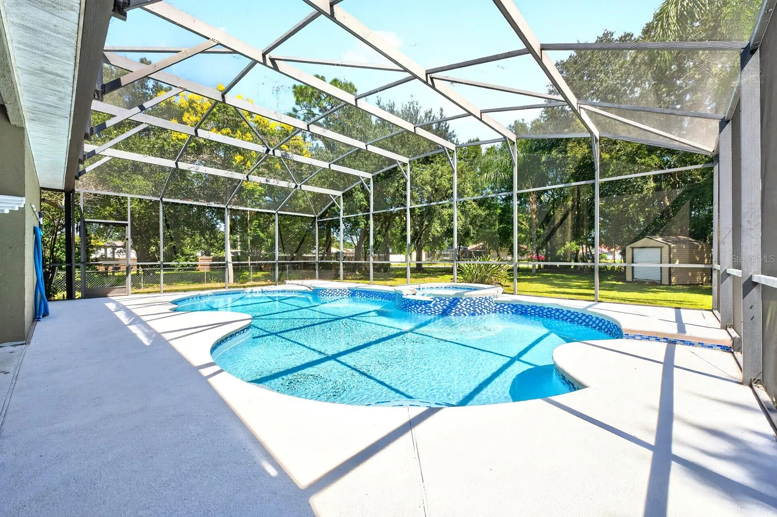 The NEWLY RESURFACED INGROUND POOL AND SPA are nestled beneath an oversized screened lanai.