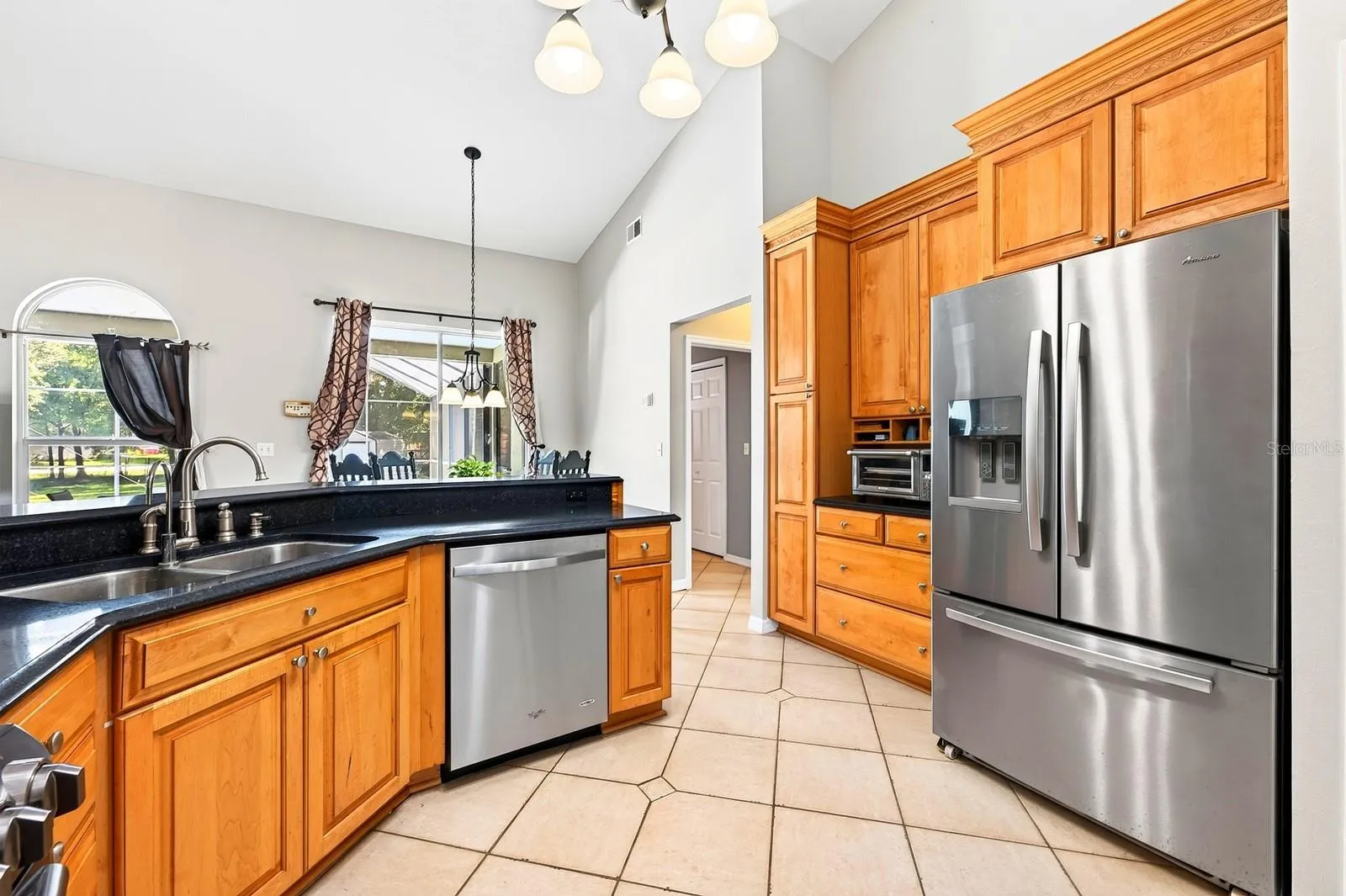 The Kitchen is both spacious and functional, featuring an abundance of SOLID-WOOD CABINETRY, generous counter space, modern tile backsplash, STAINLESS-STEEL APPLIANCES, pantry closet and breakfast bar.