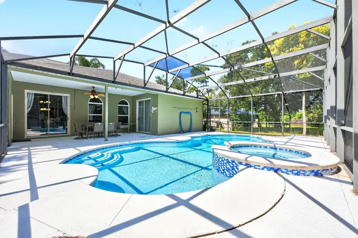 The NEWLY RESURFACED INGROUND POOL AND SPA are nestled beneath an oversized screened lanai.