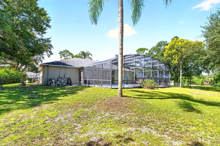 Beyond the lanai, the FENCED BACKYARD offers plenty of room to enjoy the outdoors, with mature trees providing shade and privacy.