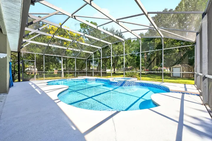 The NEWLY RESURFACED INGROUND POOL AND SPA are nestled beneath an oversized screened lanai.