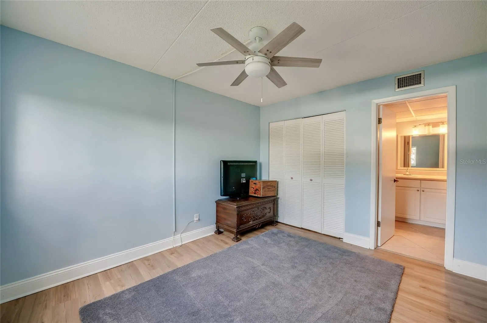 Bright and airy bedroom featuring a ceiling fan, ample closet space, and direct access to the en-suite vanity area.