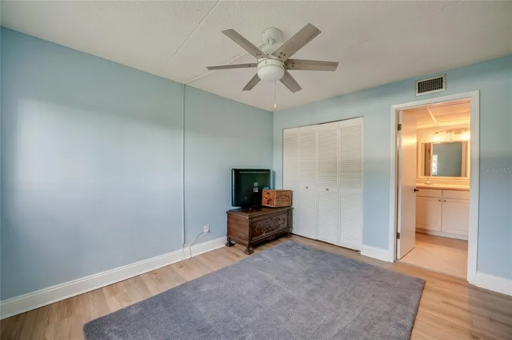 Bright and airy bedroom featuring a ceiling fan, ample closet space, and direct access to the en-suite vanity area.