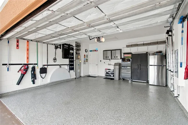 Garage w/shark coating floor, cabinets, refrigerator and tool racks