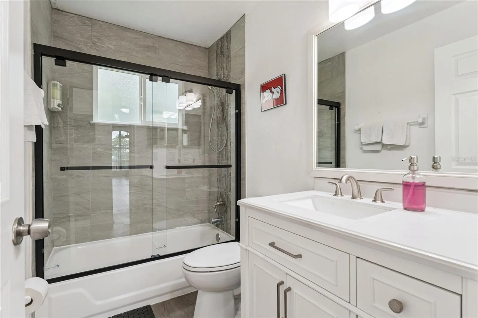Full Bathroom &amp; Shower: Updated full bathroom complete with a white vanity, modern matte black sliding glass shower doors, and sleek tile surround.