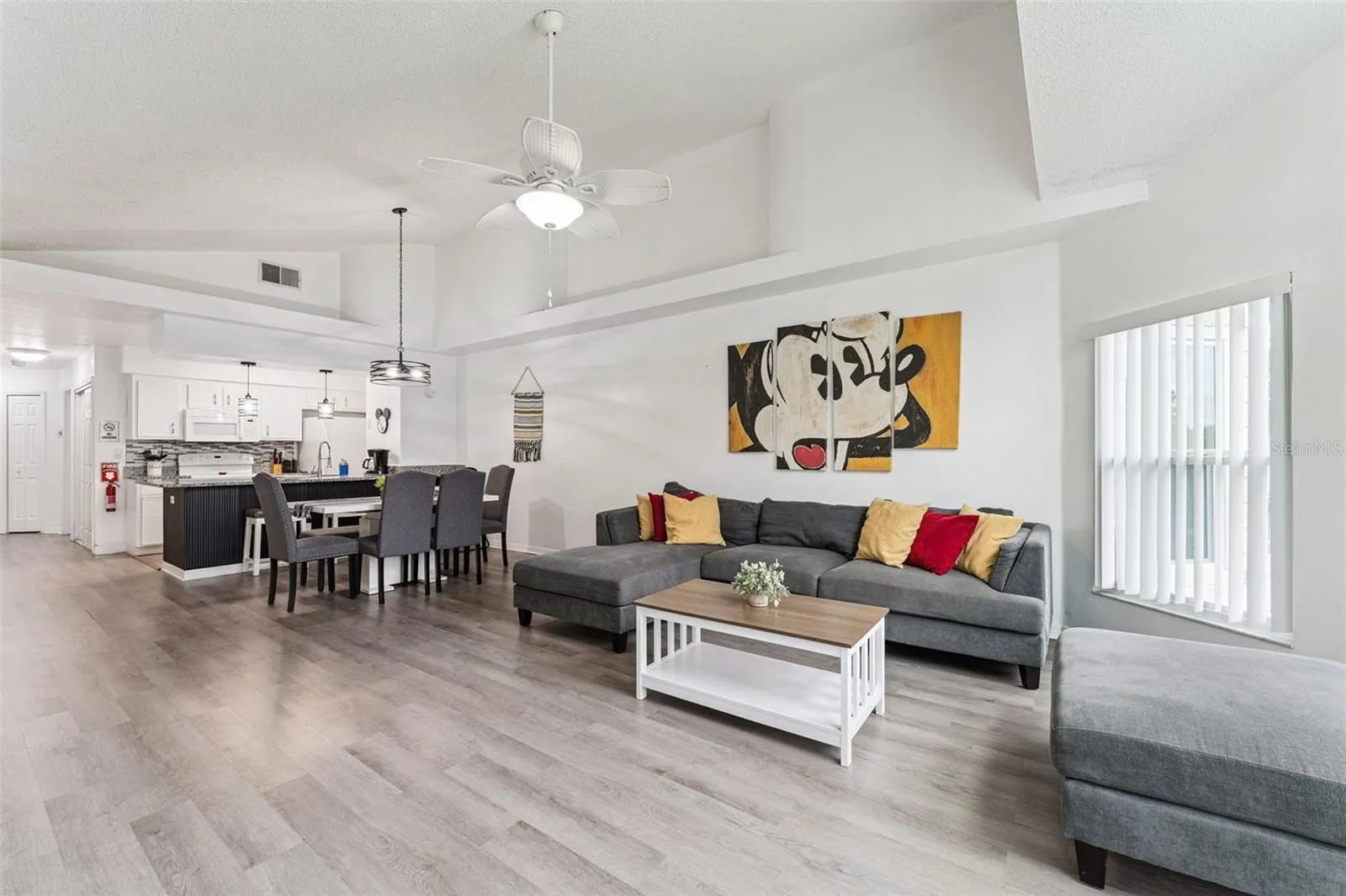 Open-Concept Living &amp; Dining: Open-plan main floor seamlessly connecting the spacious living area, dining space, and adjacent kitchen under vaulted ceilings.
