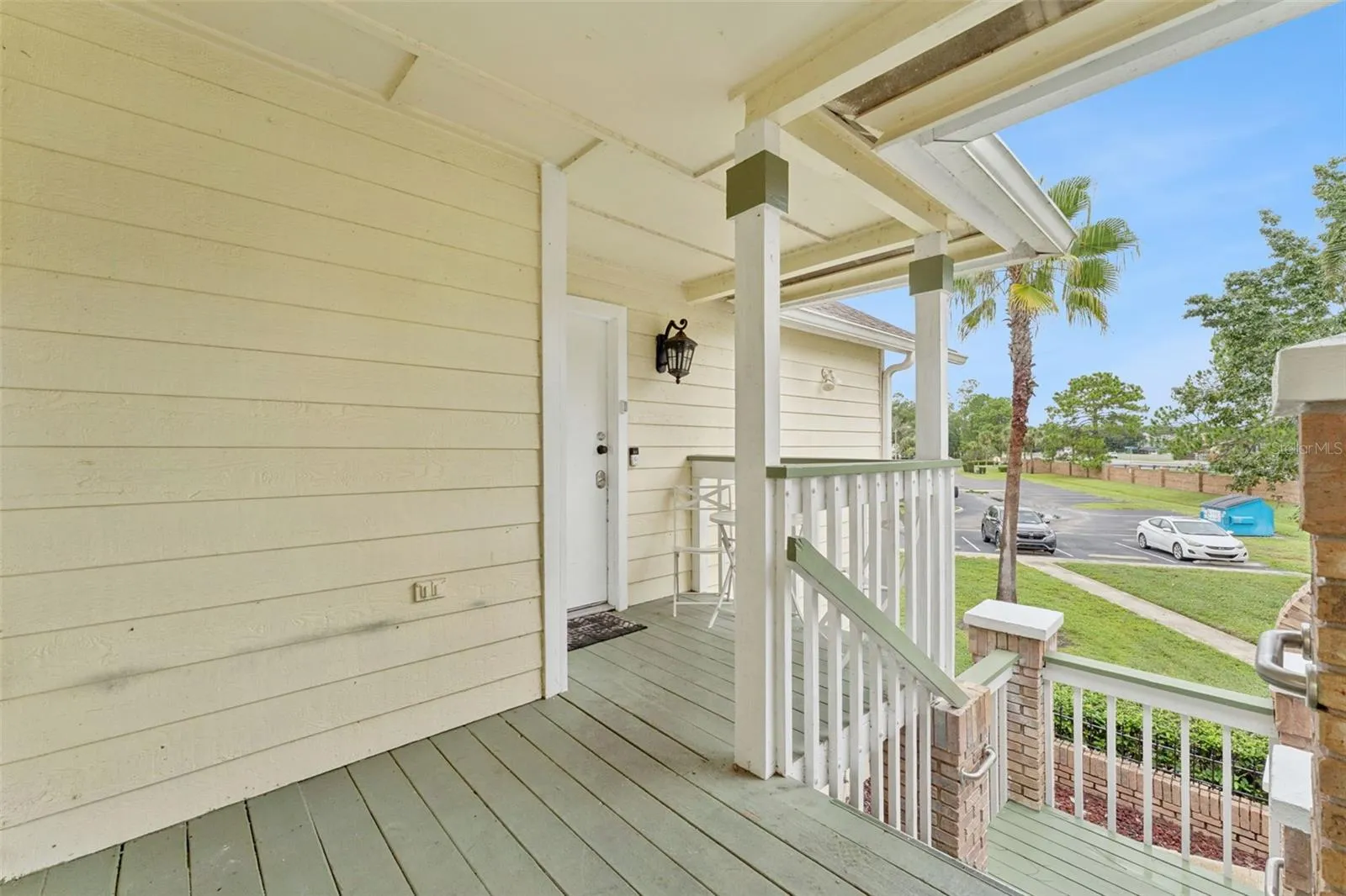 Covered Entry Deck: Covered front porch featuring painted wood decking, classic railing, brick column accents, and entry lighting