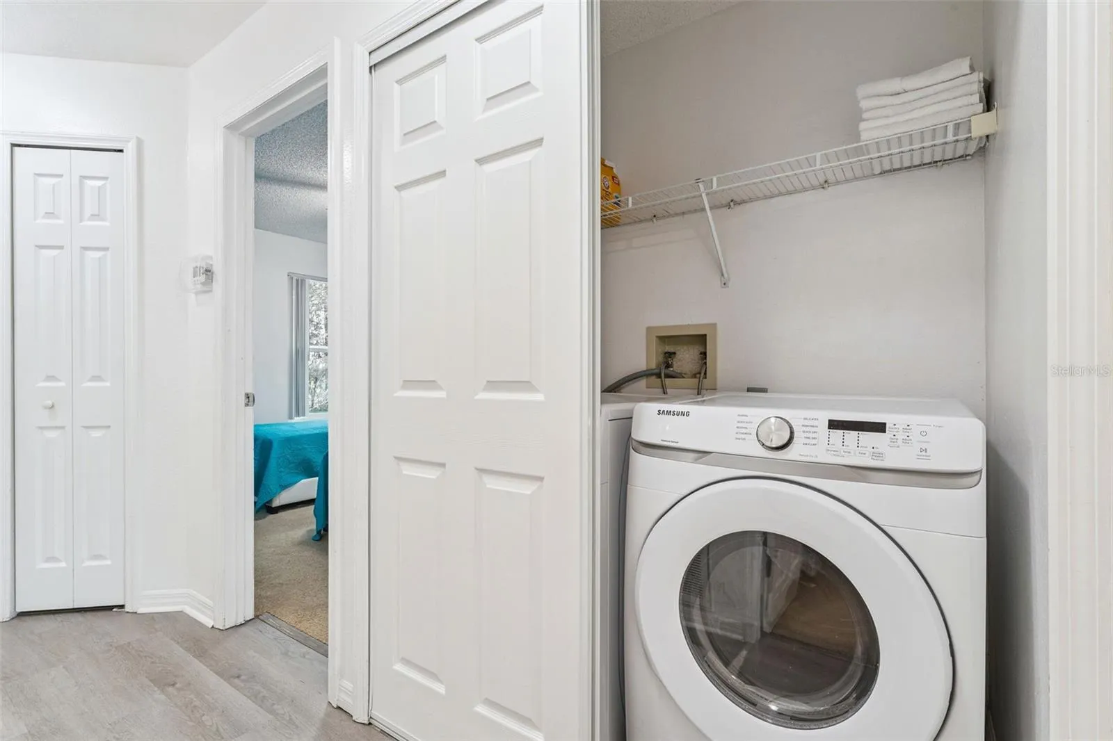 In-Unit Laundry Closet: Convenient in-unit laundry closet featuring a front-loading Samsung washer and built-in wire storage shelving