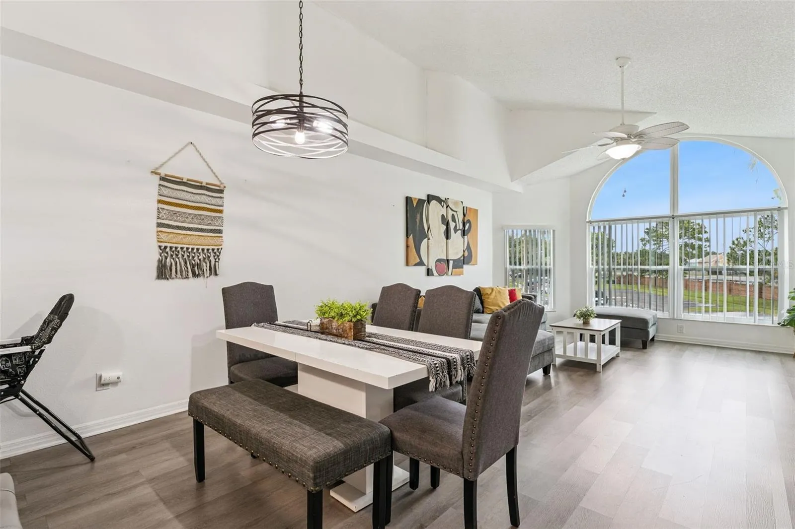 Dining Area: Dining space featuring an overhead modern chandelier fixture, dining table with bench seating, and smooth flow into the main living room.