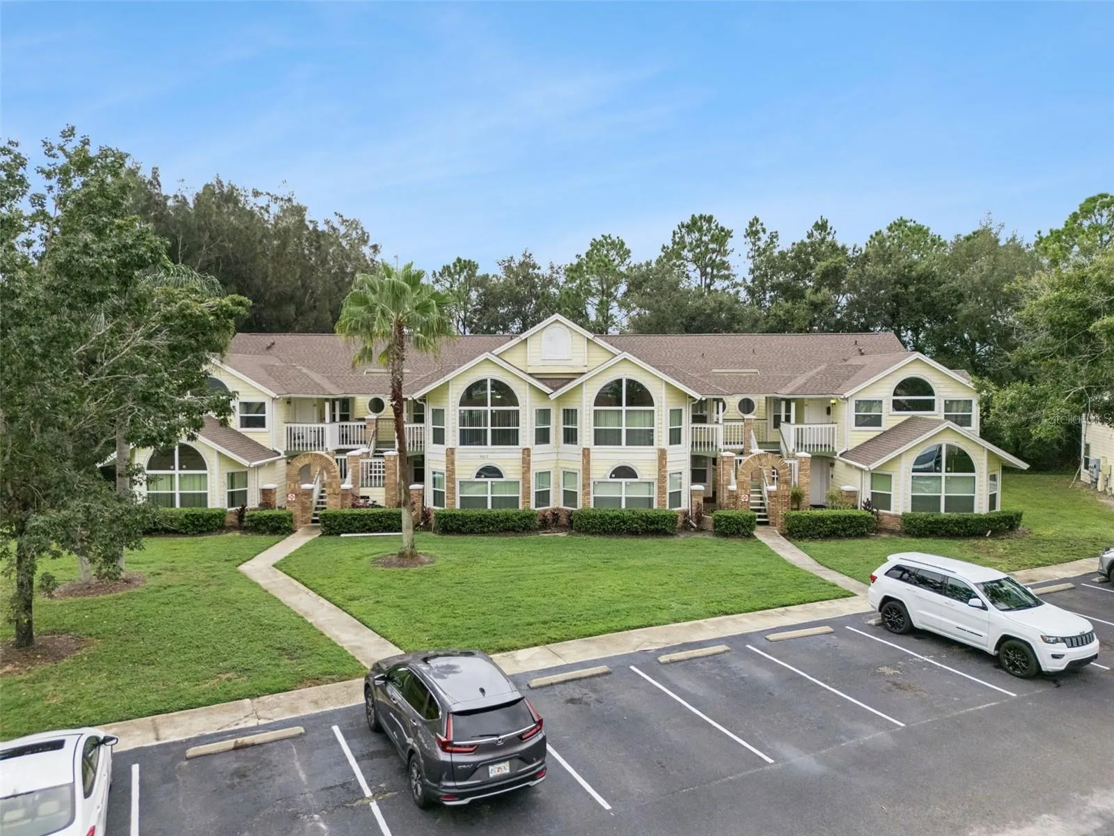 Front Elevation View: Low-angle drone photo showcasing the full building exterior, grand architectural arched windows, entry staircases, and front parking lot.