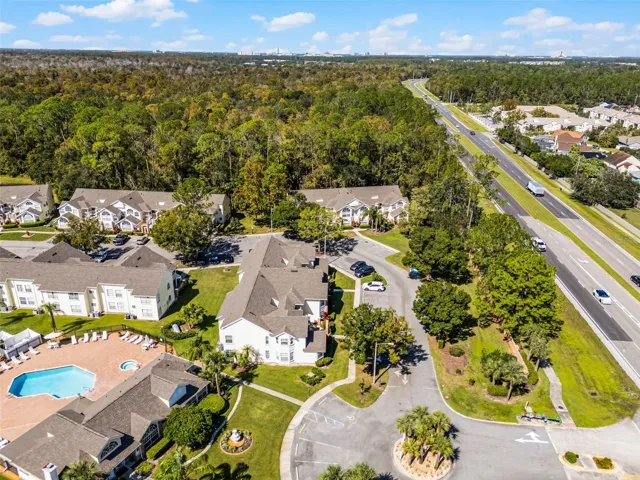 Community Entrance &amp; Highway Proximity: Aerial overview featuring the main community drive, entrance roundabout, amenity center, and adjacent major roadway for easy commuting.