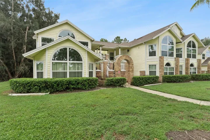 Exterior Side View: Angled building view highlighting grand arched windows, brick accents, low-maintenance hedge landscaping, and lush lawn.