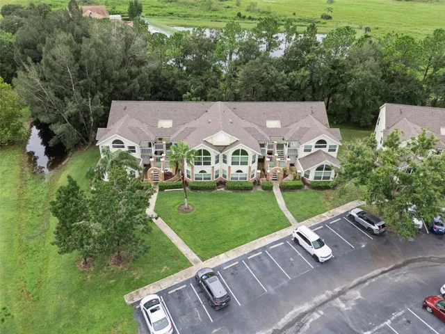 Building Aerial Overview: Elevated drone shot showing the front building elevation, manicured lawn, and convenient resident parking spaces