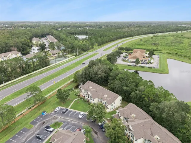 Community Layout Aerial: Angled aerial perspective showcasing the residential building relative to nearby community amenities, water features, and main road