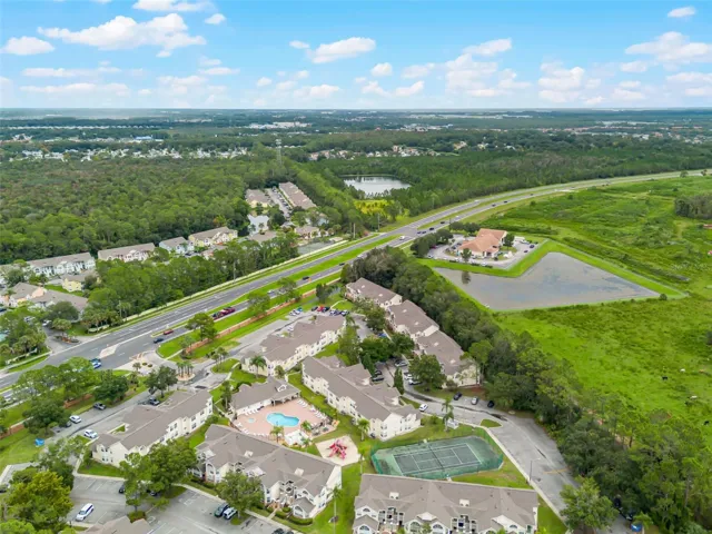Community &amp; Highway Aerial: High-angle drone shot capturing the full neighborhood grounds, recreational amenities, retention ponds, and direct access to nearby thoroughfares.
