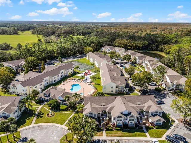 Community Grounds Aerial: High-angle drone perspective emphasizing the expansive community layout, amenity center, and tree-lined perimeter.