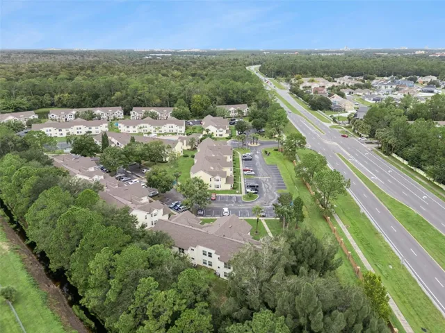 Panoramic Community View: Panoramic drone view capturing the expansive residential complex layout, mature tree canopy, water features, and regional connectivity.