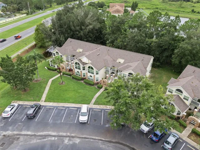 Front Aerial &amp; Parking: High-angle front aerial view of the building, highlighting convenient front parking stalls, paved walkways, and lush surrounding greenery.