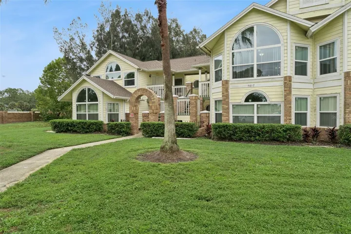 Front Walkway &amp; Entry: Paver walkway leading up to the brick entry archway, framed by mature palm trees and green space.