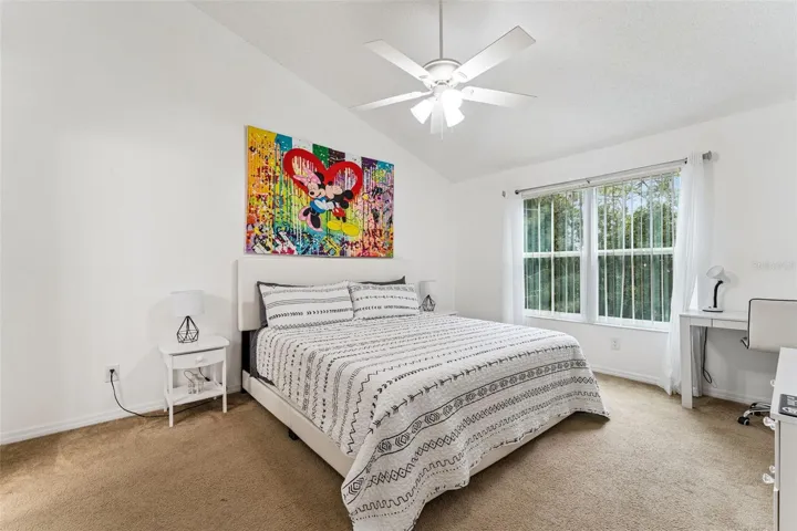 Primary Suite Alternate Angle: Spacious primary suite showing room for a king bed, nightstands, decorative wall art, and cozy carpet flooring under high ceilings.