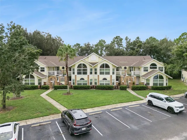 Front Elevation View: Low-angle drone photo showcasing the full building exterior, grand architectural arched windows, entry staircases, and front parking lot.