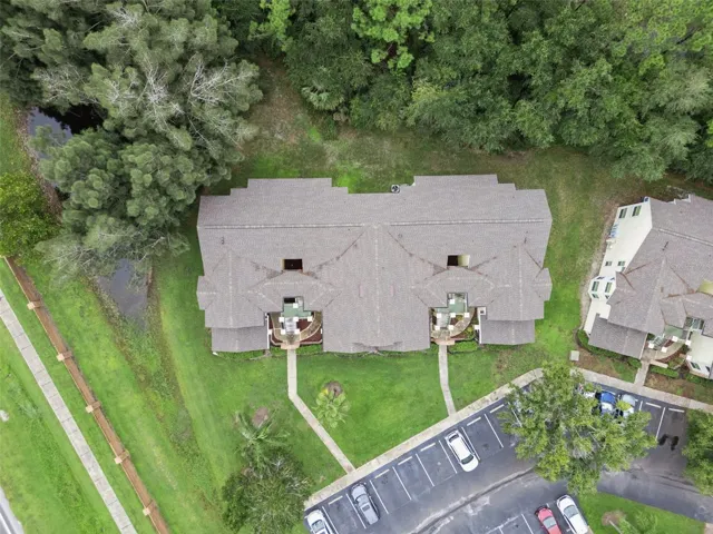 Top-Down Aerial View: Direct overhead drone perspective highlighting the building roofline, front entryway paths, and mature tree borders