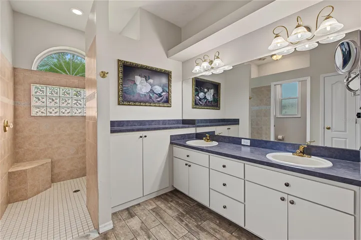 Primary Bathroom with a large walk-in shower, double vanities, tile flooring.