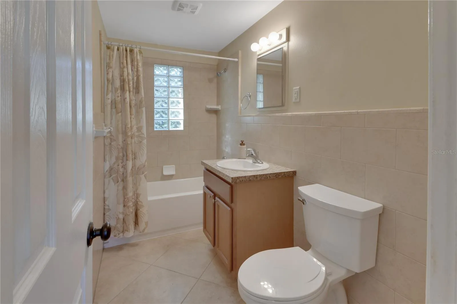 Spacious bathroom with tiled walls and new toilet