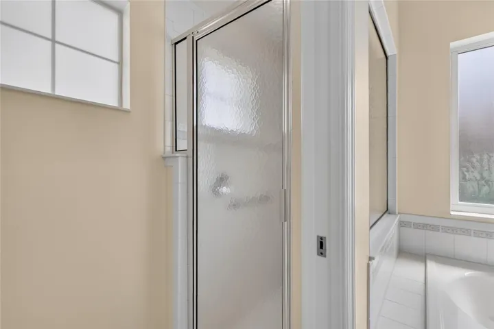 The walk in shower is separate from the tub and sink area.