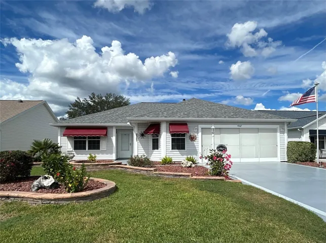 Beautifully manicured landscaping, elegant tiered garden beds, and charming burgundy awnings create irresistible curb appeal!