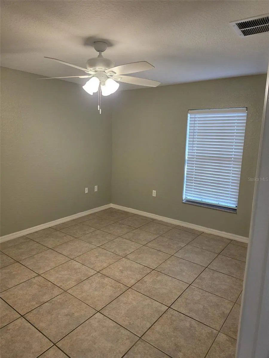 Primary bedroom with tile floors and ceiling fan
