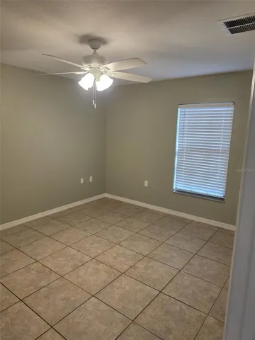 Primary bedroom with tile floors and ceiling fan