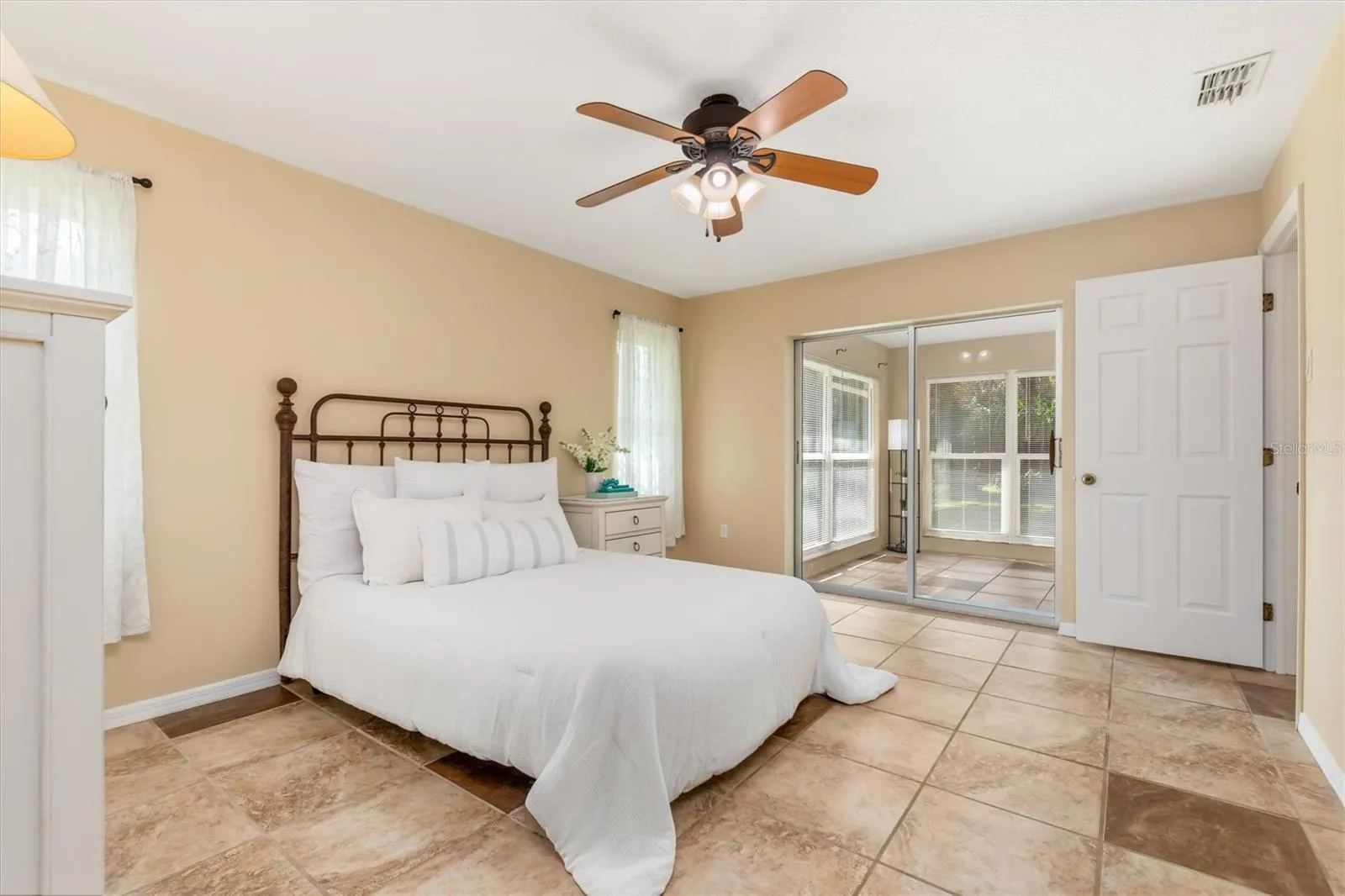 primary bedroom looking out sliding doors to lanai and pool views