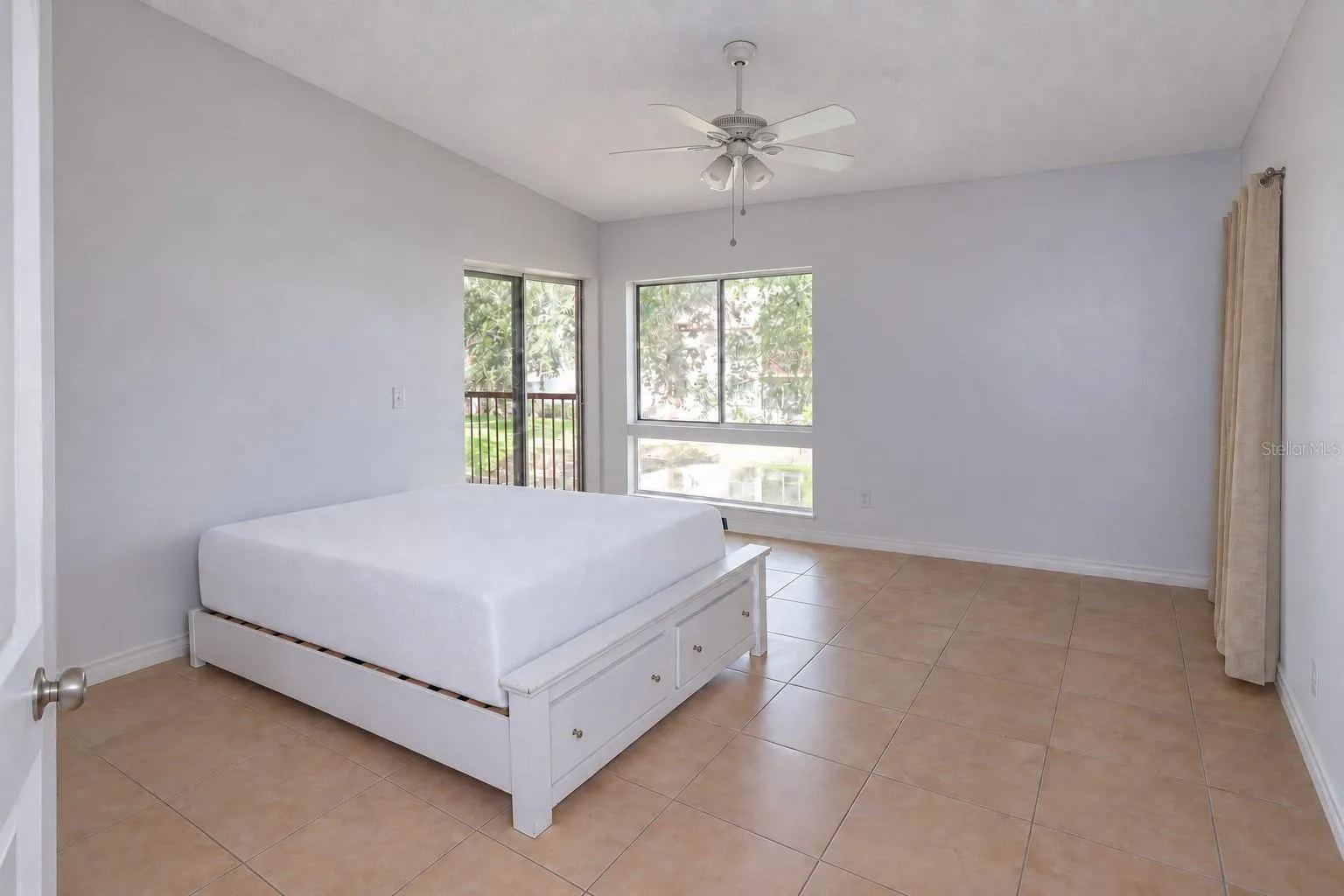 Bedroom 2 with pond view and slider access to balcony. One closet at right; a second one left of the entry door.